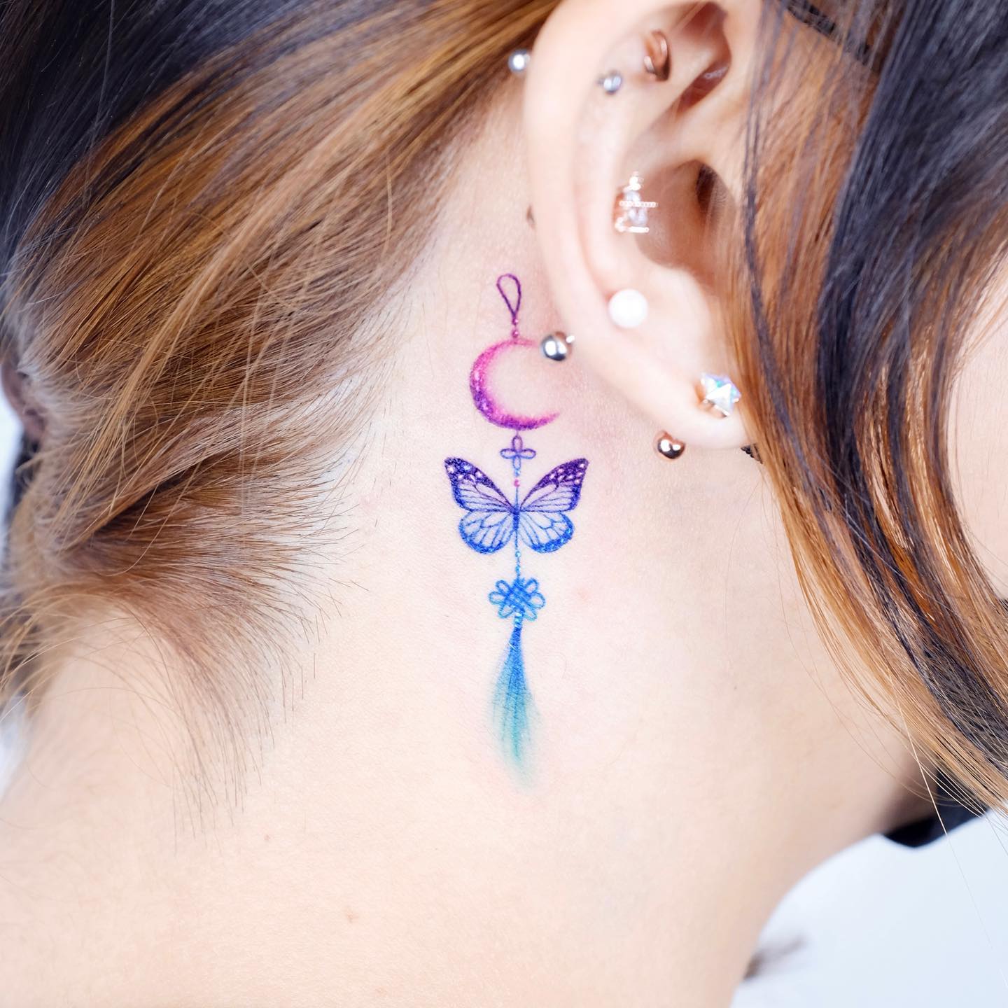 Behind the ear butterfly tattoo with moon symbol