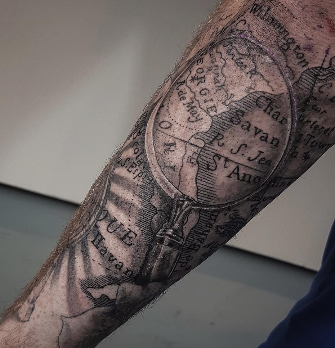 Black 3D Magnifying Glass and Maps Tattoo on Arm